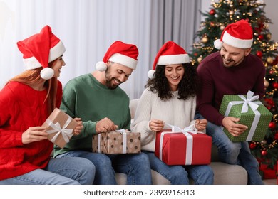 Christmas celebration in circle of friends. Happy woman and man opening gifts at home - Powered by Shutterstock