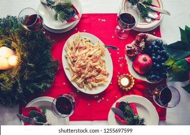 Christmas Celebration Dinner Table With Pasta And Fruits. Festive Place Setting For Holiday With Natural Decorations From Fir Tree Branches. Family Gathering Concept. Top View. Flat Lay.