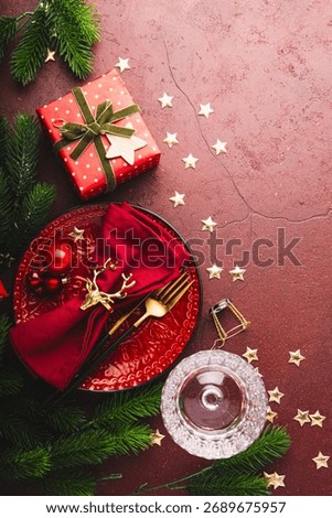 Christmas celebration table setup. Christmas table setting, empty red plate with napkin, wine glass and Christmas decorations, vertical card