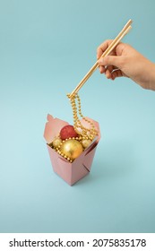 Christmas And Chinese New Year Scene, Creative Woman Hand Hold Sticks On Fast Food With Happy Background. Xmas Decoration Creative Concept With Copy Space. Minimal On Pink With Christmas Baubles