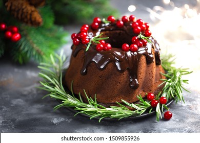 Christmas chocolate bundt cake with glaze decorated with fresh berries and rosemary. Winter baking at Xmas or New Year with decorations on dark background - Powered by Shutterstock