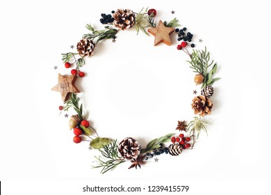 Christmas circle floral composition. Wreath of cypress, eucalyptus branches, pine cones, rowan berries, anise, confetti stars and sea holly flowers on white background. Winter wedding design. Flat lay - Powered by Shutterstock