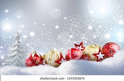 Christmas colorful layout. Christmas golden balls, red stars and Christmas tree on snow in winter snowdrift on silvery sparkling background with falling snow and copy space - Powered by Shutterstock