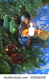Christmas composition, candle holder in the shape of the silhouette of a girl with a cup, fir branches, candle flame