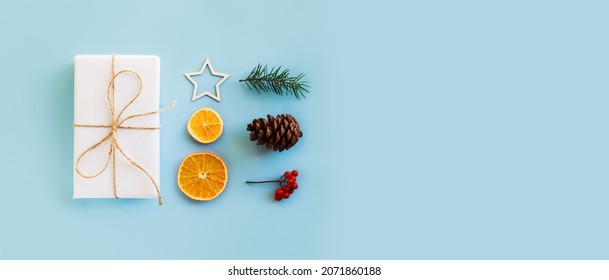 Christmas composition with eco crafted gift, dried orange, cone, xmas tree, gift and wood star. Natural minimal new year concept, top view, isolated, flat lay, copy space on blue background, banner - Shutterstock ID 2071860188