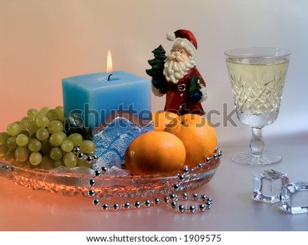 Christmas composition with fruits, candle, Santa Claus and  wineglass.