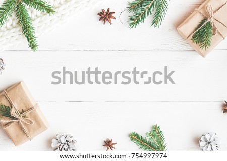 Christmas composition. Christmas gifts, fir tree branches, knitted blanket on white wooden background. Flat lay, top view, copy space.