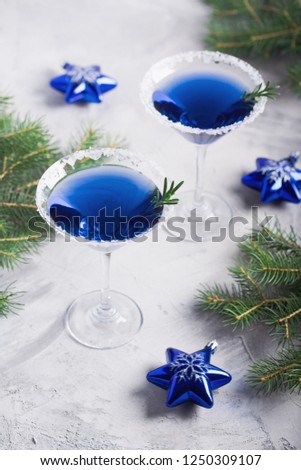 Christmas composition with martini drinks with rosemary and sugar decoration, fir-trees, stars, in blue colors, gray concrete background. Winter holiday, New Year party concept.