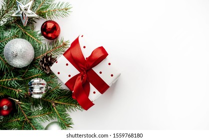 
Christmas composition on a white background with white gift boxes, with a red ribbon with fir branches, toys, copy space for your congratulations