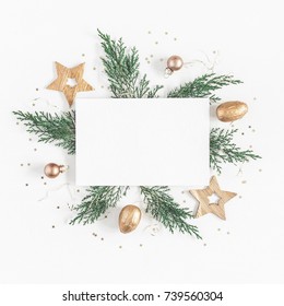 Christmas composition. Paper blank, christmas tree branches, golden decorations on white background. Flat lay, top view, copy space, square.