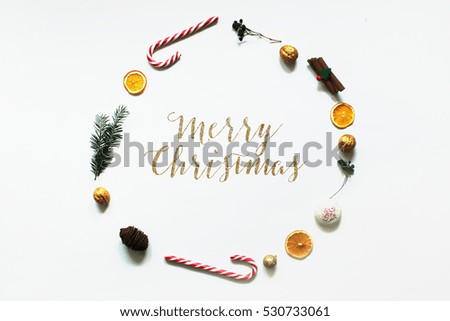 Christmas composition. christmas round frame, candy cane orange cinnamon sticks gingerbread tree walnuts top view merry christmas text on white background flat lay copy space 