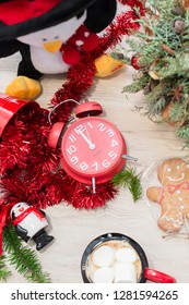 Christmas composition at the table with the decor, a mug of marshmallows in the form of a snowman, a penguin, gingerbread and a  clock
