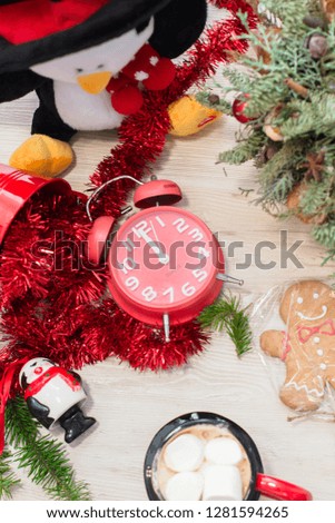 Christmas composition at the table with the decor, a mug of marshmallows in the form of a snowman, a penguin, gingerbread and a  clock