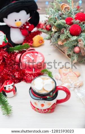 Christmas composition at the table with a decor, a snowman mug, a penguin and a red clock