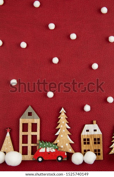 Christmas composition with\
toy  wooden houses over the red background. Seasonal holidays,\
greeting card, invitation for xmas party concept. Flat lay. Top\
view