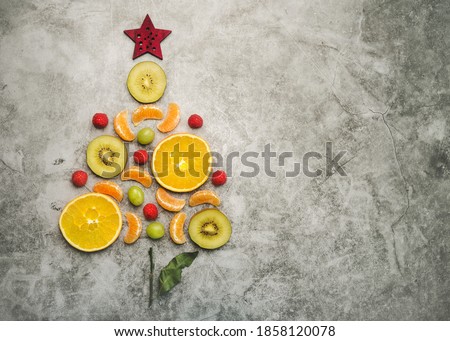 Christmas concept background. Pieces of fruit in the form of a christmas tree on gray background