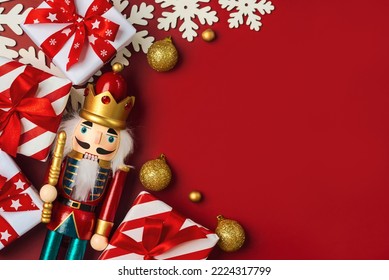 Christmas concept background. Top view of Christmas ornament and christmas wooden nutcracker toy solider with space for text over a red background

