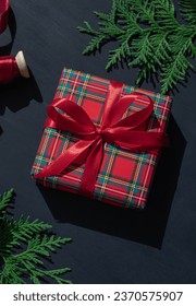 Christmas concept composition with tartan pattern gift box on the dark blue wooden background. Winter holiday greeting card. 