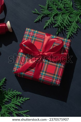 Christmas concept composition with tartan pattern gift box on the dark blue wooden background. Winter holiday greeting card. 