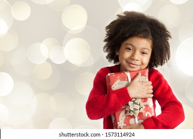 Christmas concept. Happy adorable african american child girl with christmas gift in hands on light background. - Powered by Shutterstock