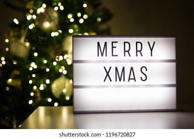 christmas concept - lihtbox with merry xmas words in dark room with decorated christmas tree - Powered by Shutterstock