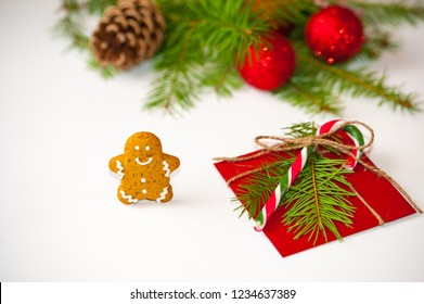 Christmas concept: red envelope decorated with a pine branch and christmas candy cane on on white background with traditional christmas gingerbread pastries. Copy space. - Shutterstock ID 1234637389