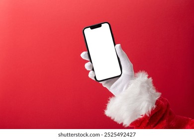 Christmas concept, Santa Claus hand holding a smartphone with blank screen with copy space on red background - Powered by Shutterstock