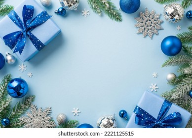 Christmas concept. Top view photo of blue silver baubles disco balls snowflake ornaments present boxes with bows pine branches confetti on isolated light blue background with empty space in the middle - Powered by Shutterstock