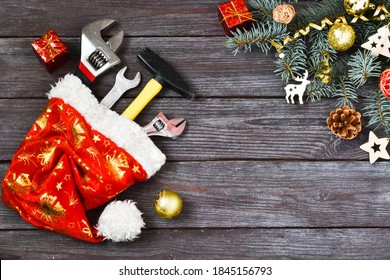 Christmas construction tools. A hammer, a wrench, an adjustable wrench in a Santa Claus hat near a spruce branch on a wooden background. Advertising concept. Greeting card. Copy space, flat lay. - Powered by Shutterstock