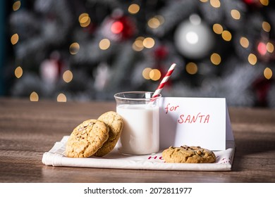 christmas cookies with a glass of milk and a letter for santa on background of blurred lights - Powered by Shutterstock