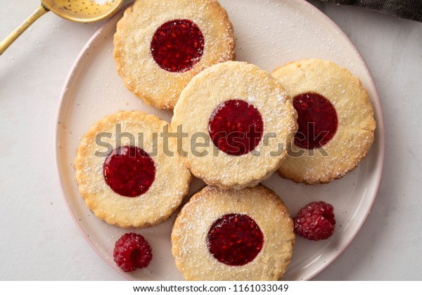 Christmas cookies. Linzer cookies with raspberry\
jam on white table background. Traditional Austrian biscuits\
filled. Top view and copy\
space