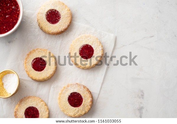 Christmas cookies. Linzer cookies with raspberry\
jam on white table background. Traditional Austrian biscuits\
filled. Top view and copy\
space