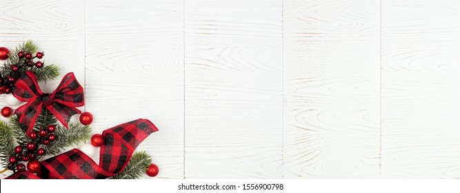 Christmas Corner Border Banner Of Ornaments, Branches And Red And Black Checked Buffalo Plaid Ribbon. Above View On A White Wood Background.