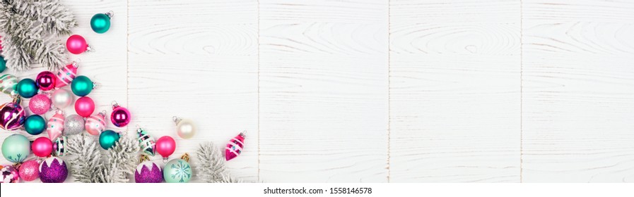 Christmas Corner Border Banner With Pink, Purple And Teal Baubles And Tree Branches. Above View On A White Wood Background.