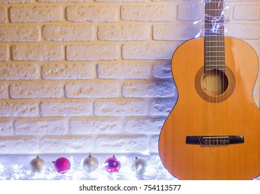 Christmas Country Music With Acoustic Guitar And Holiday Lighted Garlands On Brick Wall