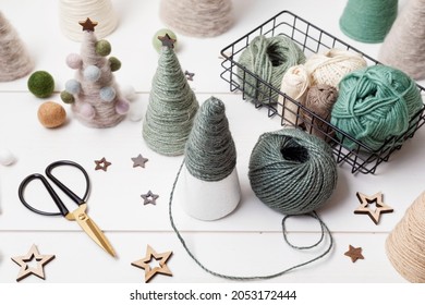 Christmas Craft Hobby Background With Handmade Yarn Cone Xmas Trees In Natural Colors. Recomforting, Destressing Hobby To Make Christmas Decoration. Top View Of Diy Workshop