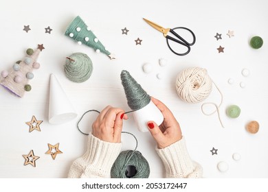 Christmas Craft Hobby Background With Handmade Yarn Cone Xmas Trees In Natural Colors. Recomforting, Destressing Hobby To Make Christmas Decoration. Top View Of Diy Workshop