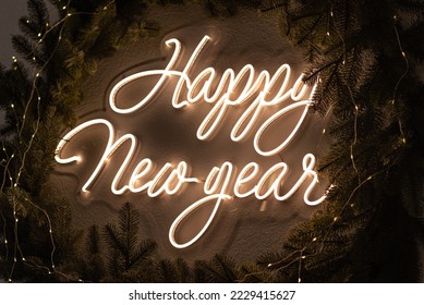 Christmas decor. A flexible neon sign with the words Happy New Year hanging on the wall. Around the wreath of Christmas tree branches. Celebration of new year, christmas - Powered by Shutterstock