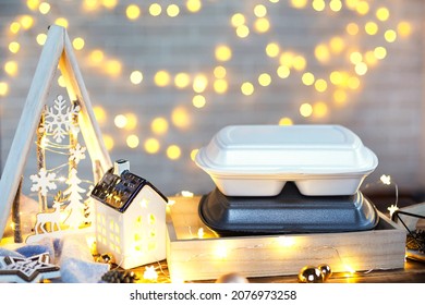 Christmas Decor Of Food Delivery Service Containers. New Year's Eve Promotion. Ready-made Hot Order, Disposable Plastic Box In Fairy Light. Work On Public Holidays Catering. Copy Space, Mock Up