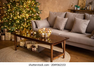 Christmas decor in a loft-style apartment. Large Christmas tree, sofa, coffee table. Cozy brown interior decorated with garlands.