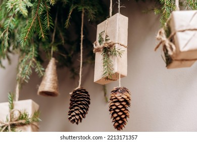 Christmas decor on the wall.Fir branches decorated with gift boxes in craft paper and fir cones.Eco-friendly concept.New Year and Christmas concept.Selective focis,close up. - Shutterstock ID 2213171357