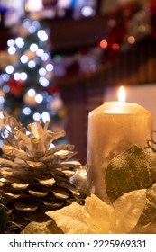 Christmas Decoration With A Centerpiece With A Candle, A Tree In The Background And A Fireplace
