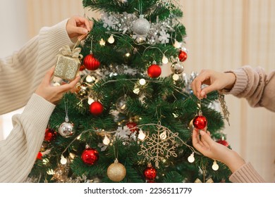 Christmas decoration concept, Two women wears reindeer horns and decorating christmas tree at home. - Powered by Shutterstock