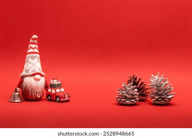 Christmas decoration, elf with pine cones, bell and small car on red background - Powered by Shutterstock