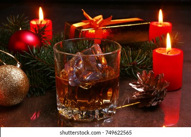 christmas decoration with glass of cognac or whiskey, red candles, gift box and christmas tree. Selective focus. - Powered by Shutterstock