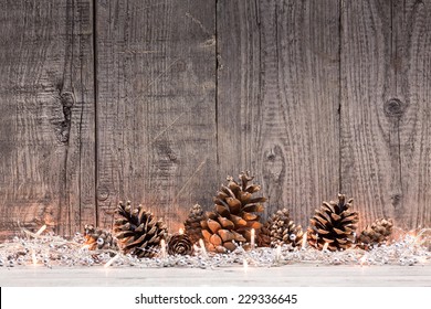 Christmas decoration with lighs and fir cones with natural wooden background