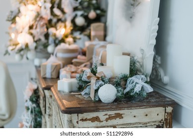 Christmas decoration on ancient vintage old commode chest of drawers. Hand made craft gifts, candels and a tree at background. Selective focus