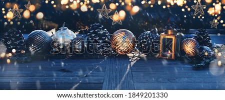 Christmas decoration on a wooden table in darkness with golden bokeh and snowflakes. Background for christmas and advent concepts with space for text.