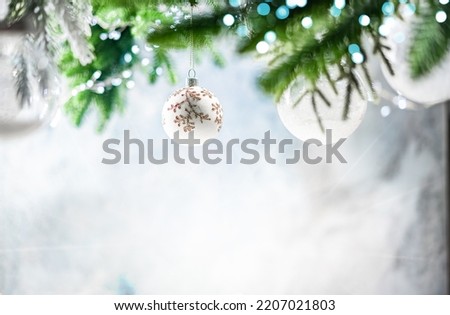 Christmas decoration with white christmas balls and fir tree branches against blurred blue background, copy space for your product or text.
