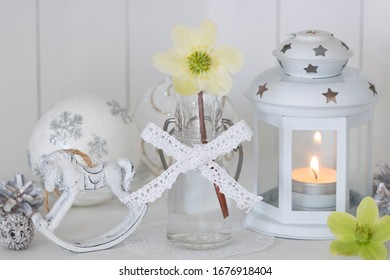 christmas decoration in white with helleborus niger in glass bottle and lantern